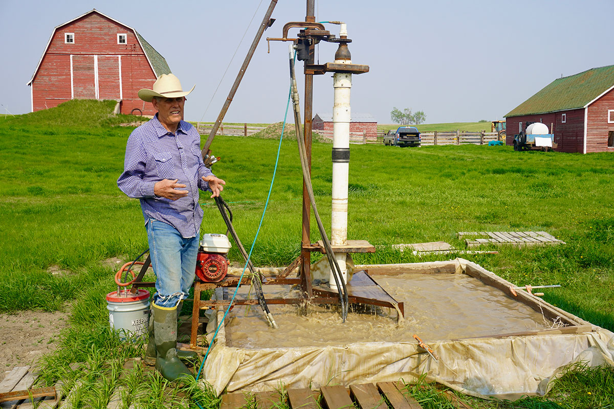 Rancher Paul Williams stands in front of his handmade drilling rig.